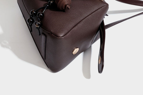 Structured trapezoid shoulder bag in dark brown pebbled leather-look finish with slim double straps, top zip closure, side