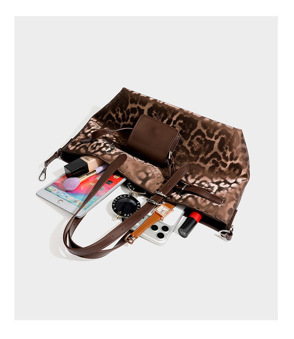 Glossy leopard-print tote bag with leather-look dark trim, dual top handles, detachable shoulder strap, and attached front