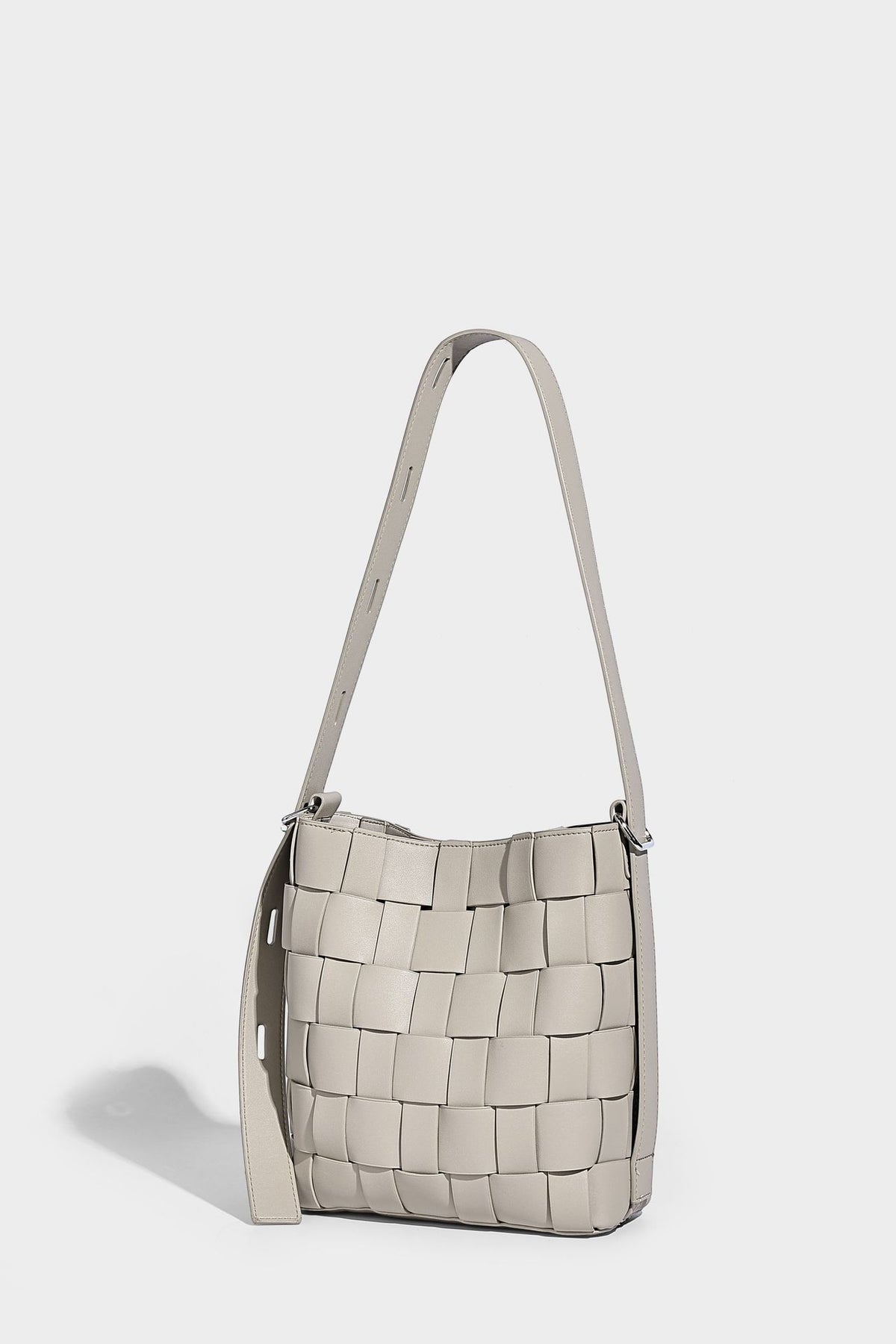 Hand-woven black-and-white checkerboard bucket bag with smooth black trim, silver-tone ring hardware, and adjustable