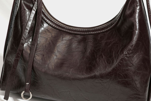 Slouchy hobo shoulder bag in glossy crinkled leather-look finish with zip-top closure and silver-tone ring hardware, detail