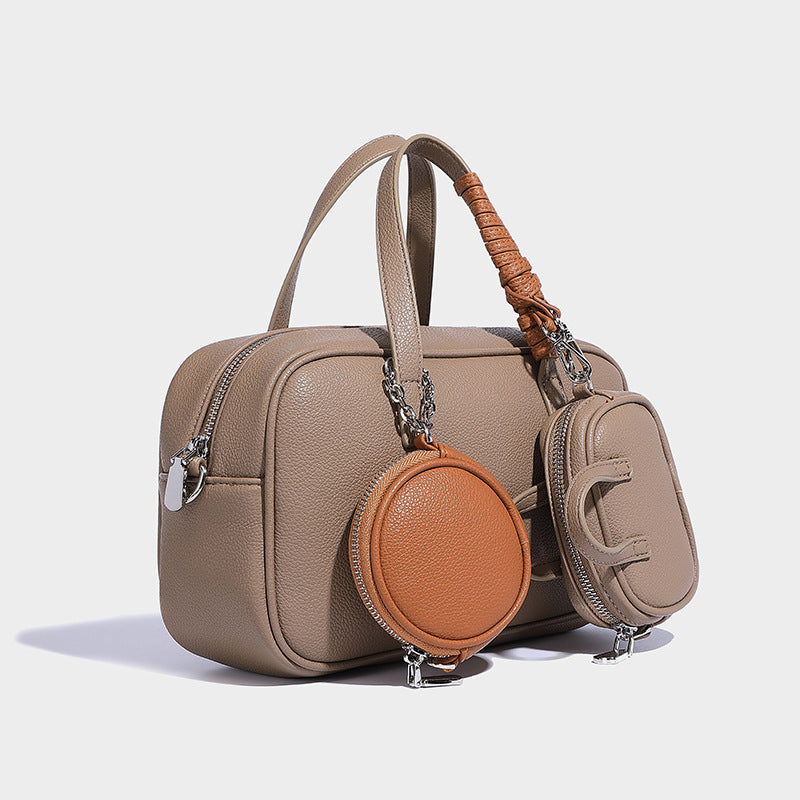 Structured pebbled leather-look Boston bowling bag in tan with blue detachable round mini pouch, dual top handles, and