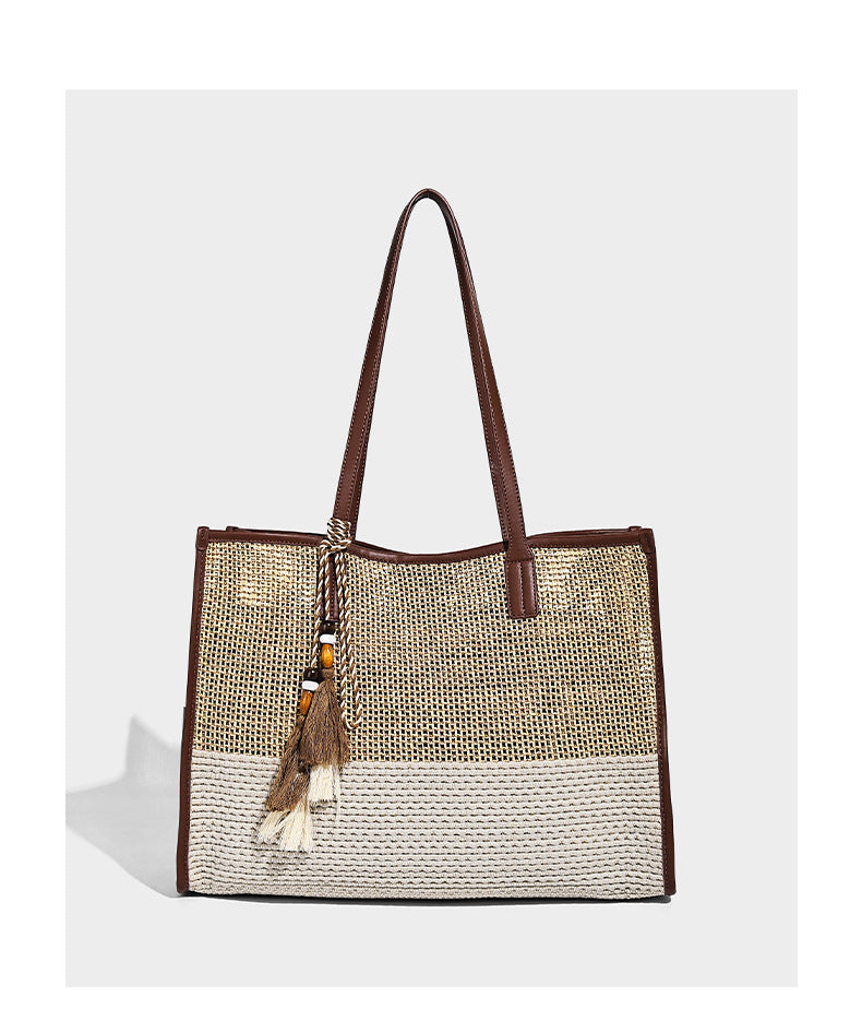 Two-tone woven straw tote bag with leather-look brown trim, long shoulder straps, and knotted tassel charm, detail view 9