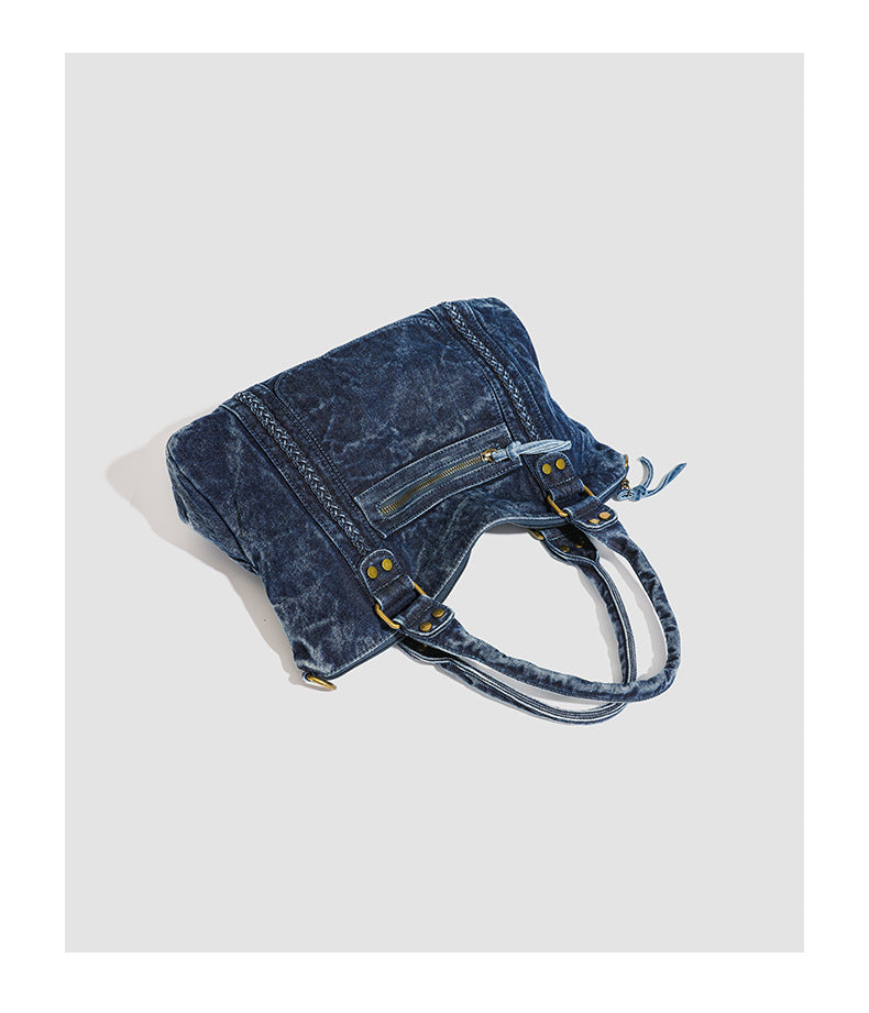 Large washed blue denim-look shoulder bag with gold-tone rings and rivets, top zip closure, front zip pocket, and adjustable