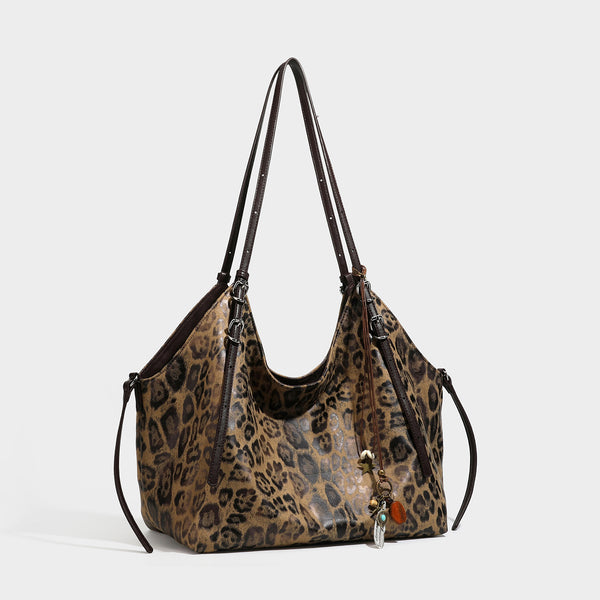 Slouchy leopard-print shoulder tote bag in tan and brown with long double straps, side tie straps, and dangling charm, detail