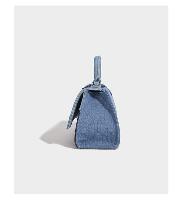 Structured patchwork denim trapezoid satchel bag with frayed panel trim, rounded top handle, and silver-tone hardware, detail