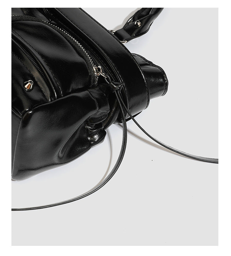 Black glossy structured tote bag with rivet and buckle detail, dual top handles, and detachable shoulder strap, detail view