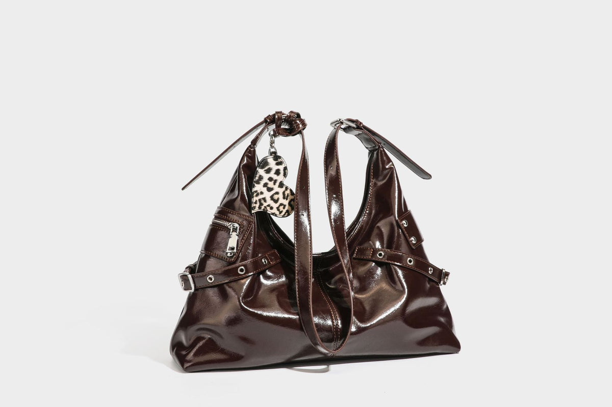 Glänzende dunkelbraune, lässig geschnittene Hobo-Schultertasche mit Riemendetail mit silberfarbenen Ösen, Reißverschlussfach auf der Vorderseite und Herz mit Leopardenmuster