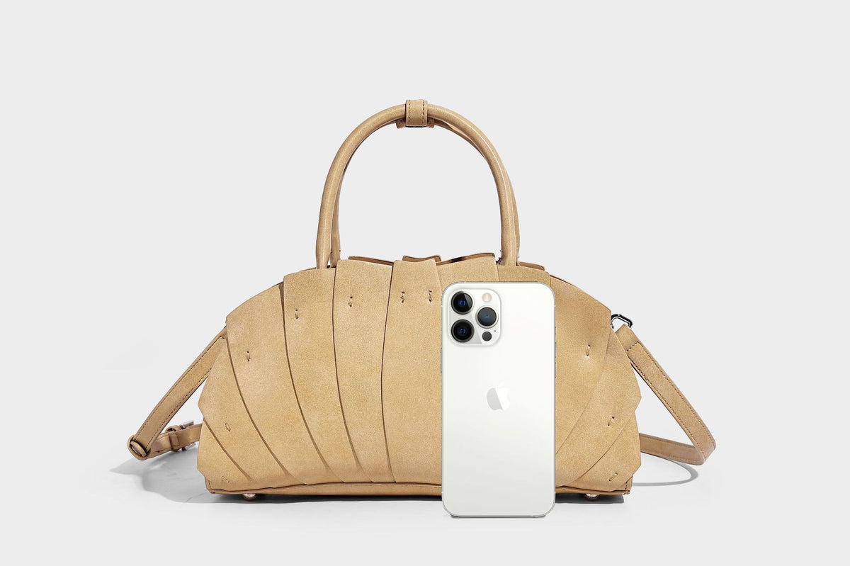 Structured dome satchel with fan-pleated leather-look exterior, dual top handles, and detachable shoulder strap, detail view