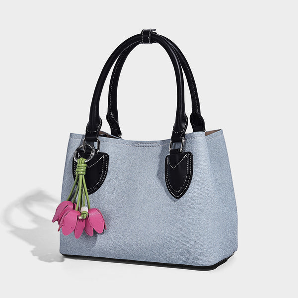 Structured light-blue denim-look tote bag with black leather-look handles, white contrast stitching, silver-tone hardware