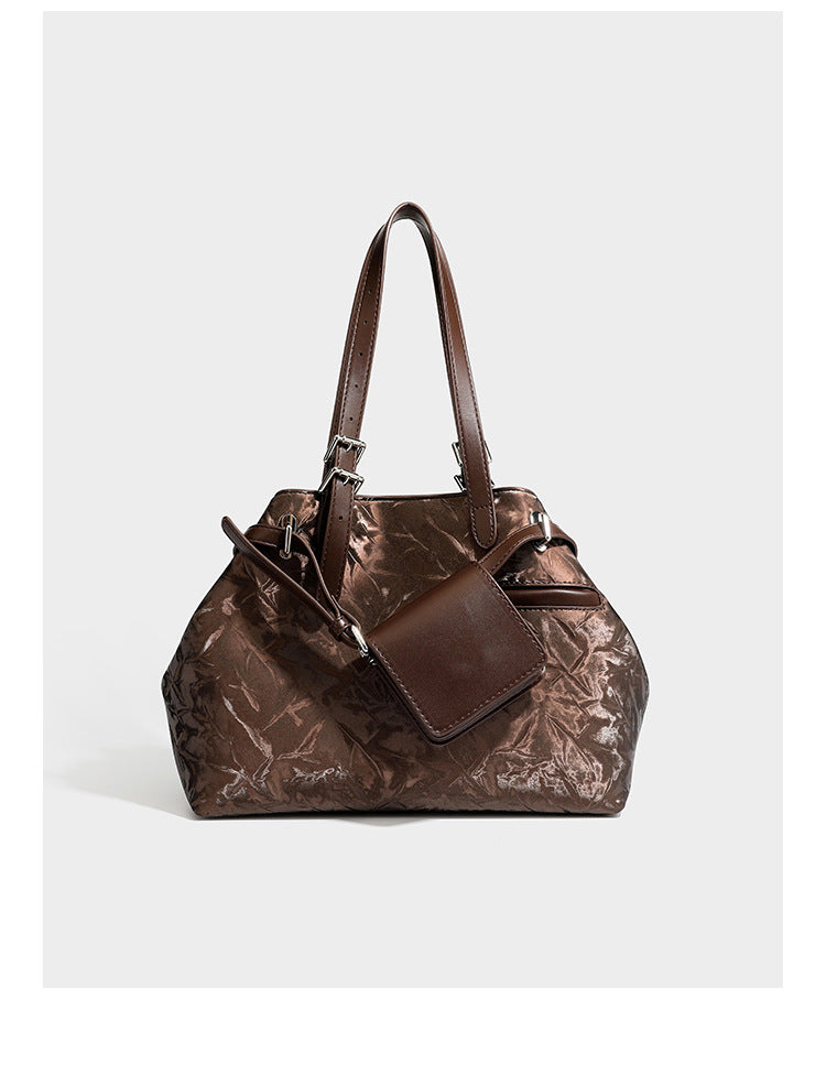 Glossy crinkled metallic-finish tote bag in brown with smooth leather-look top handles, silver-tone hardware, and attached