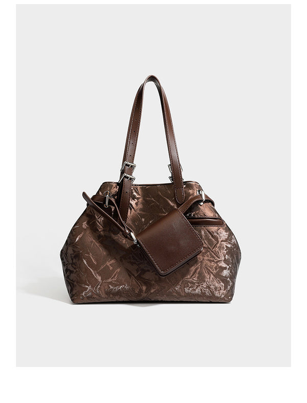 Glossy crinkled metallic-finish tote bag in brown with smooth leather-look top handles, silver-tone hardware, and attached