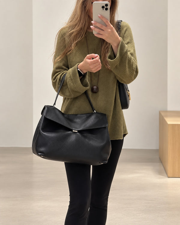 Large black slouchy leather-look shoulder bag with V-shaped envelope flap, silver-tone clasp, and adjustable strap, detail