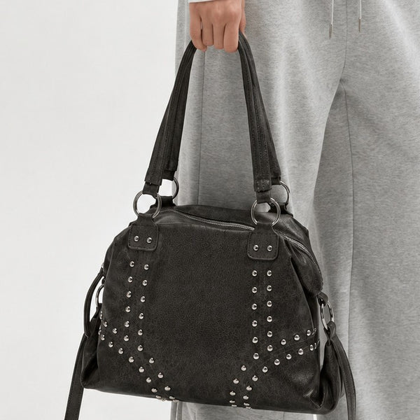 Lässige Schultertasche in dunkelgrauer genarbter Lederoptik mit silberfarbenen kuppelförmigen Nieten im Chevron-Muster, zwei Trägern mit O-Ringen und Reißverschluss oben