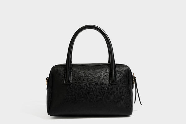 Small structured pillow satchel bag with pebbled leather-look finish, dual rolled top handles, gold-tone gourd emblem, and
