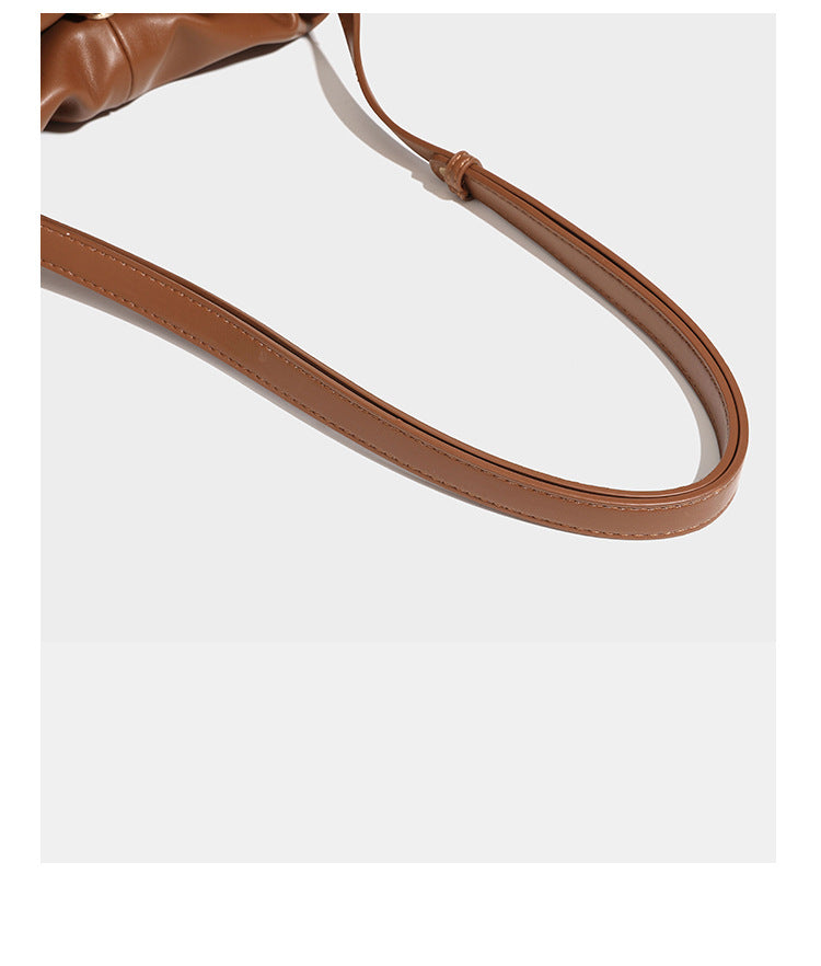 Slouchy ruched drawstring shoulder bag in smooth leather-look finish with gold-tone emblem and slim adjustable strap, detail