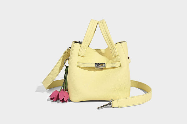 Small structured pebbled bucket tote bag with dual top handles, silver turn-lock front pocket, and detachable shoulder strap