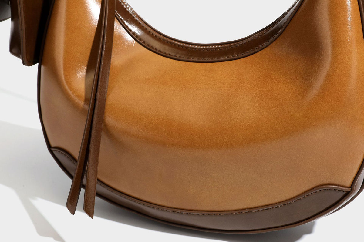 Glossy leather-look crescent hobo shoulder bag with dark contrast trim, silver-tone hardware, and attached mini flap pouch