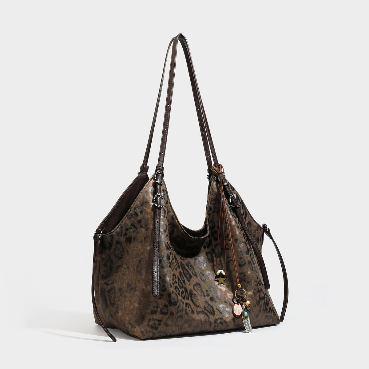 Slouchy leopard-print shoulder tote bag in tan and brown with long double straps, side tie straps, and dangling charm, front