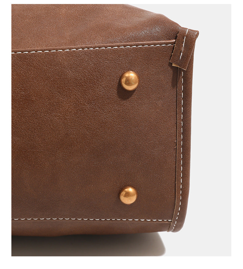 Structured leather-look flap backpack handbag with top handle, buckle front straps, white contrast stitching, and gold-tone