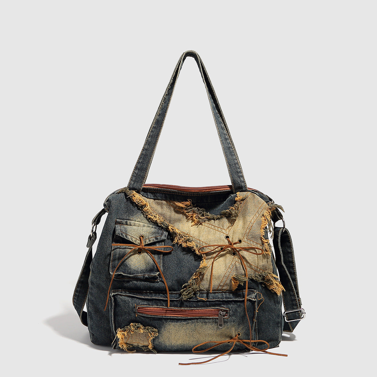 Large distressed denim patchwork shoulder tote bag with frayed panels, leather-look lace detailing, and front zip pocket in