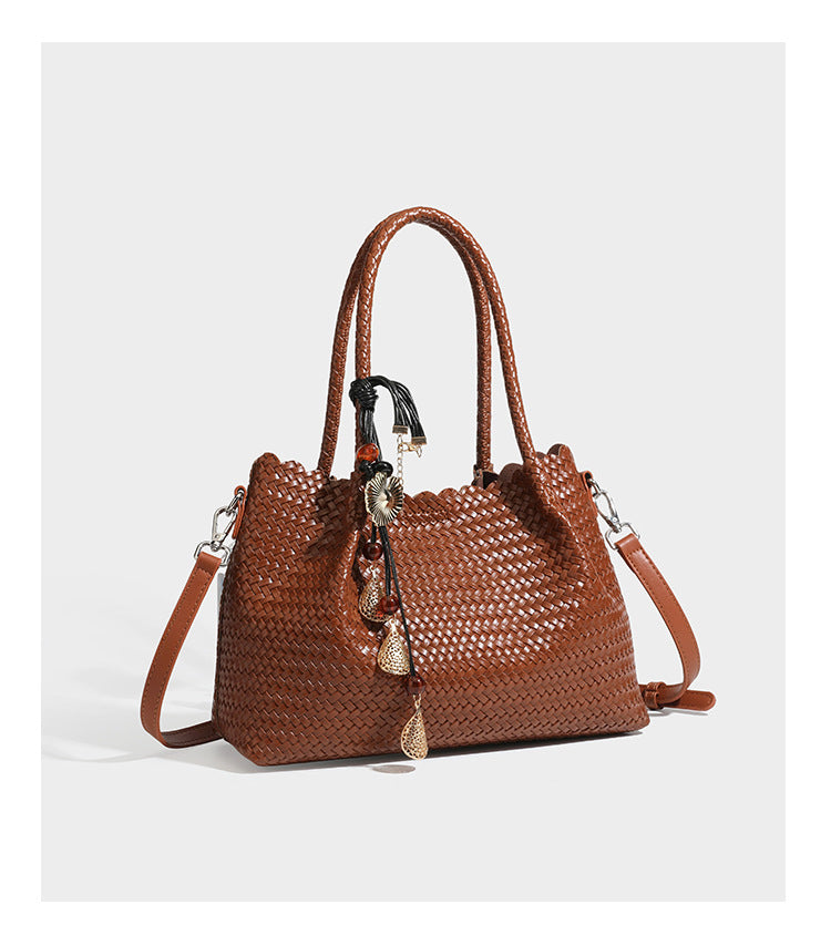 Strukturierter, glänzend geflochtener Shopper mit Muschelkantenabschluss am oberen Rand, geflochtenen Tragegriffen, abnehmbarem Crossbody-Riemen und Perlenquaste