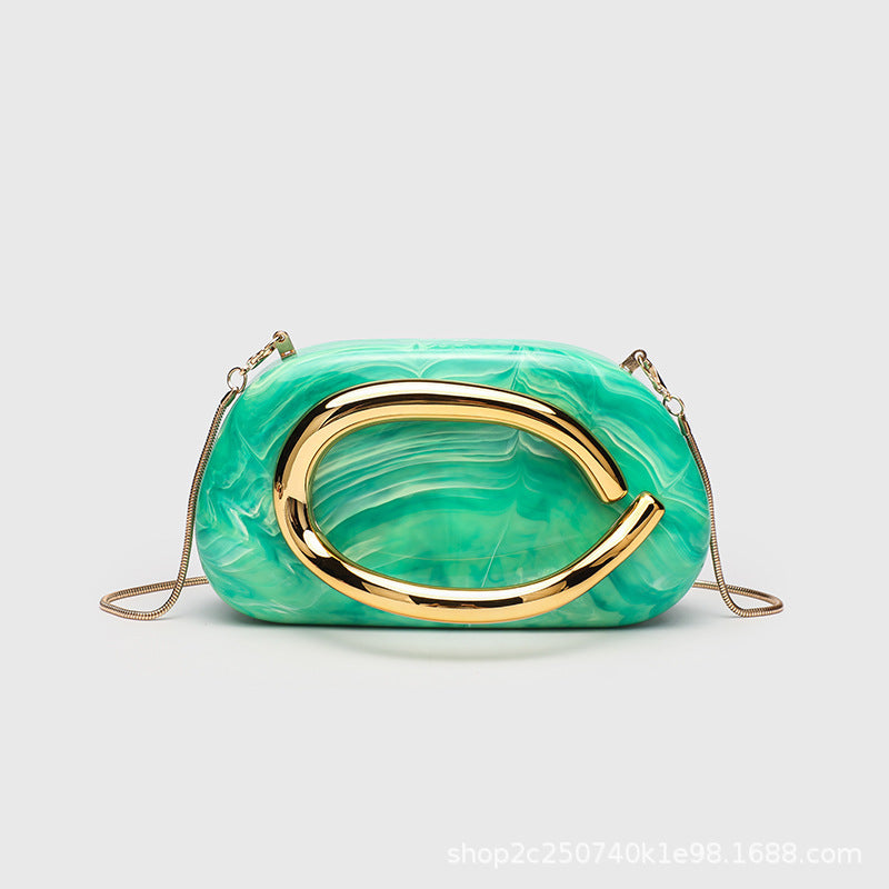 Kleine rechteckige Crossbody-Clutch mit abgerundeten Ecken, oversized poliertem C-förmigem Goldgriff und schmalem Goldkettenriemen, Detailansicht