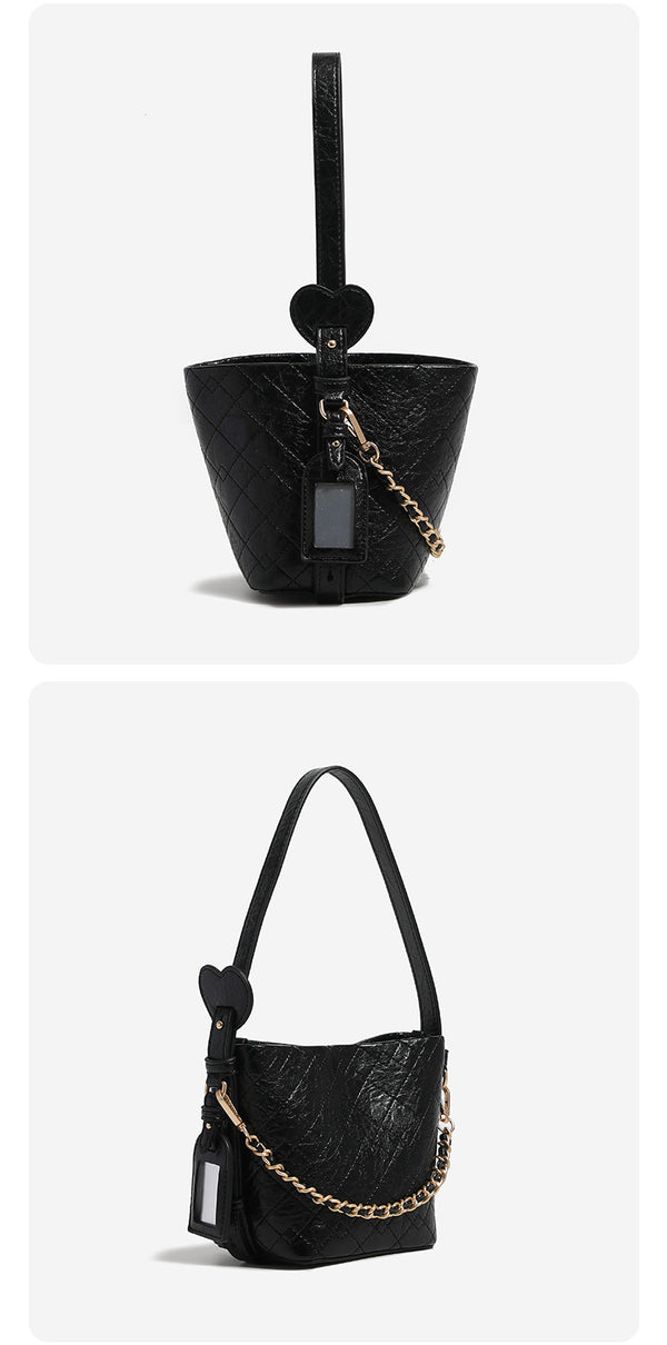 Small diamond-quilted bucket bag with gold-tone chain accent, heart strap detail, hanging tag, and matching zip coin pouch