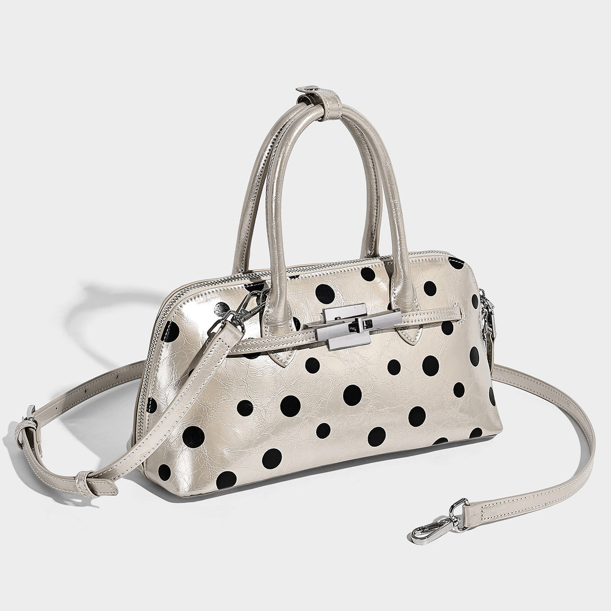 Structured polka-dot Boston bag with glossy crinkled finish, dual top handles, silver-tone turn-lock clasp, and detachable