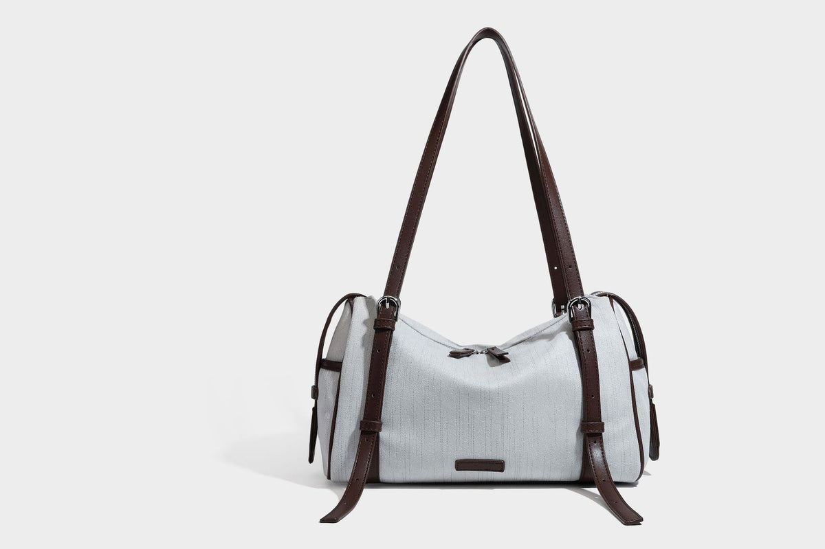 Olivgrüne Schultertasche in Zylinderform aus Canvas mit Riemen in schwarzer Lederoptik, Reißverschluss oben und silberfarbenen Beschlägen, Detailansicht