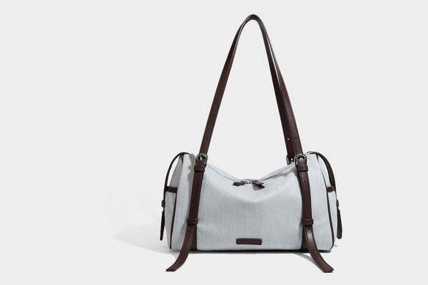 Olivgrüne Schultertasche in Zylinderform aus Canvas mit Riemen in schwarzer Lederoptik, Reißverschluss oben und silberfarbenen Beschlägen, Detailansicht