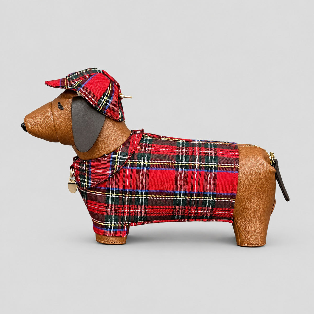 Dackelförmige Umhängetasche mit roten Tartan-Körperpartien, hellbrauner genarbter Optik, passender Tartan-Schiebermütze und goldfarbenem