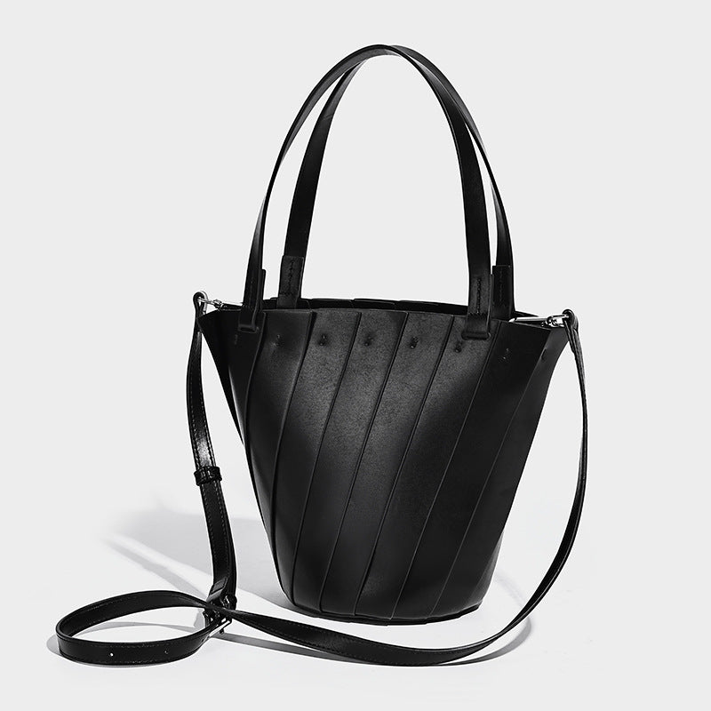 Structured bucket tote bag with vertical panel exterior, dual top handles, and detachable shoulder strap in tan leather-look