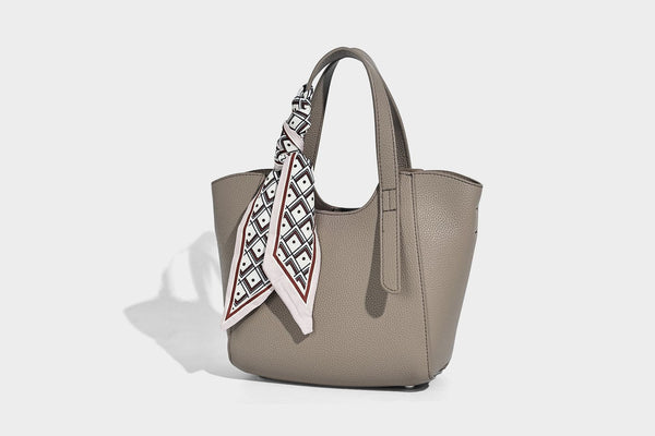 Structured pebbled leather-look tote bag with detachable scarf tie, dual top handles, and adjustable crossbody strap, detail