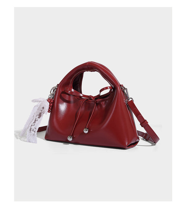 Kleine glänzende Henkeltasche in Lederoptik mit kuppelförmigem Design, Kordelzugverschluss, weißem Spitzen-Schleifenanhänger und silberfarbenen Beschlägen
