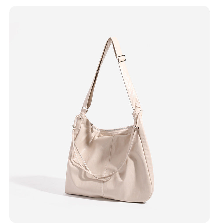 Oversized slouchy hobo shoulder bag with glossy crinkled leather-look finish, drawstring gathered sides, and silver-tone