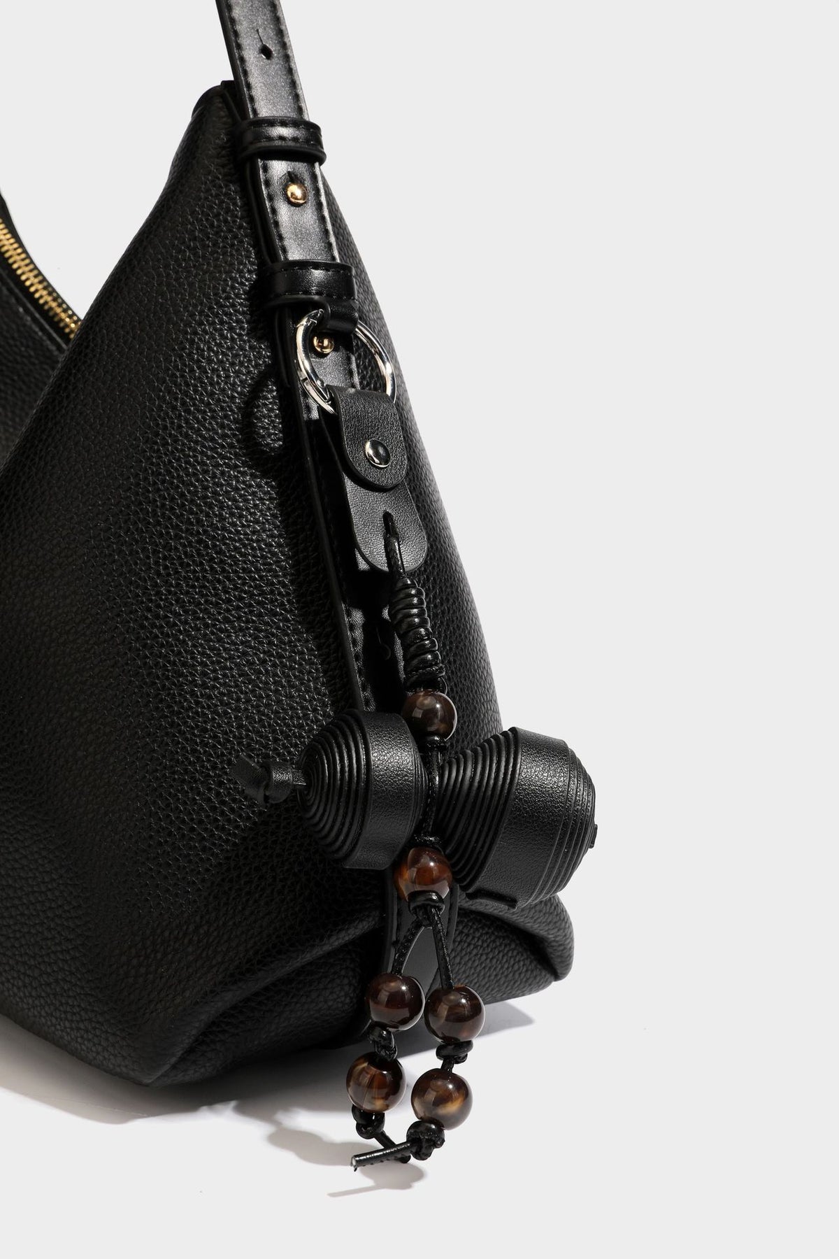 Slouchy hobo shoulder bag with pebbled leather-look finish, zip-top closure, gold-tone hardware, and hanging bead charm