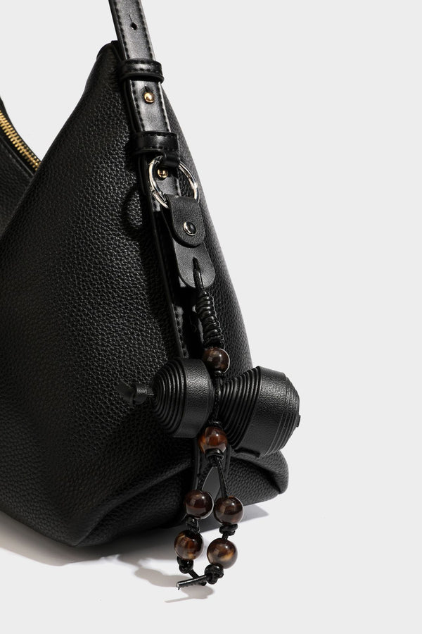 Slouchy hobo shoulder bag with pebbled leather-look finish, zip-top closure, gold-tone hardware, and hanging bead charm