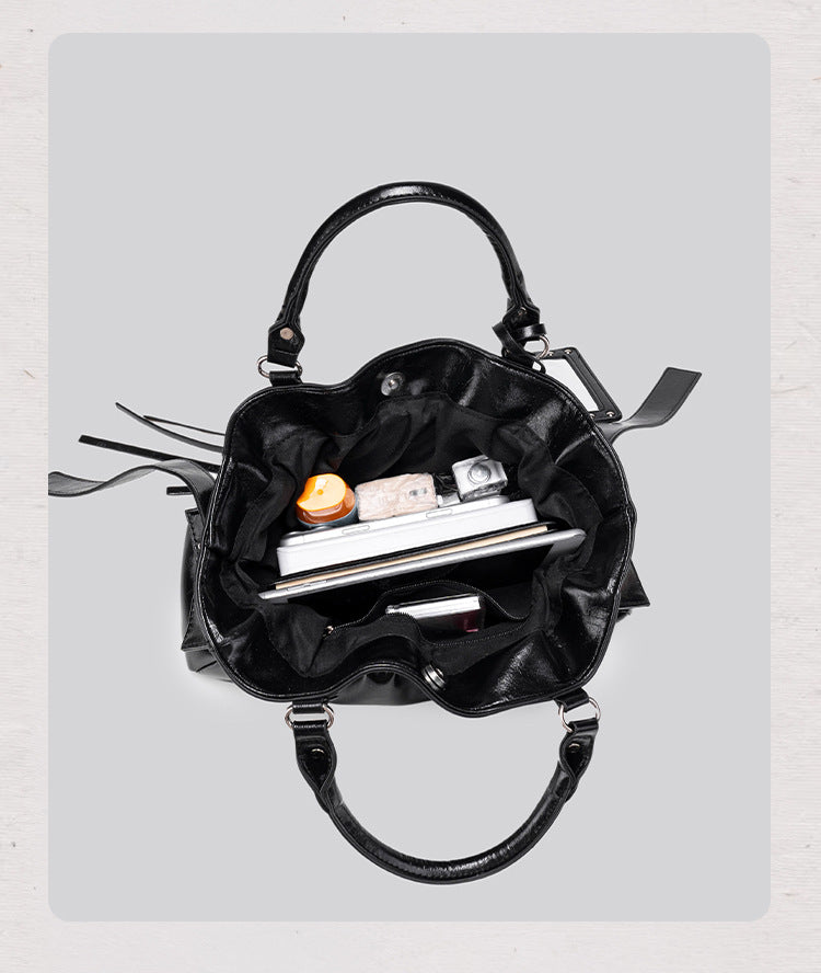 Black glossy ruched convertible tote bag with silver-tone rivets, detachable wide shoulder strap, external zip pouch, and