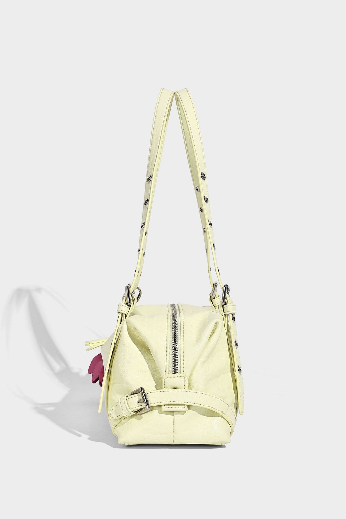 Pale yellow leather-look barrel bag with silver grommet-studded shoulder straps, top zip closure, and pink tulip floral