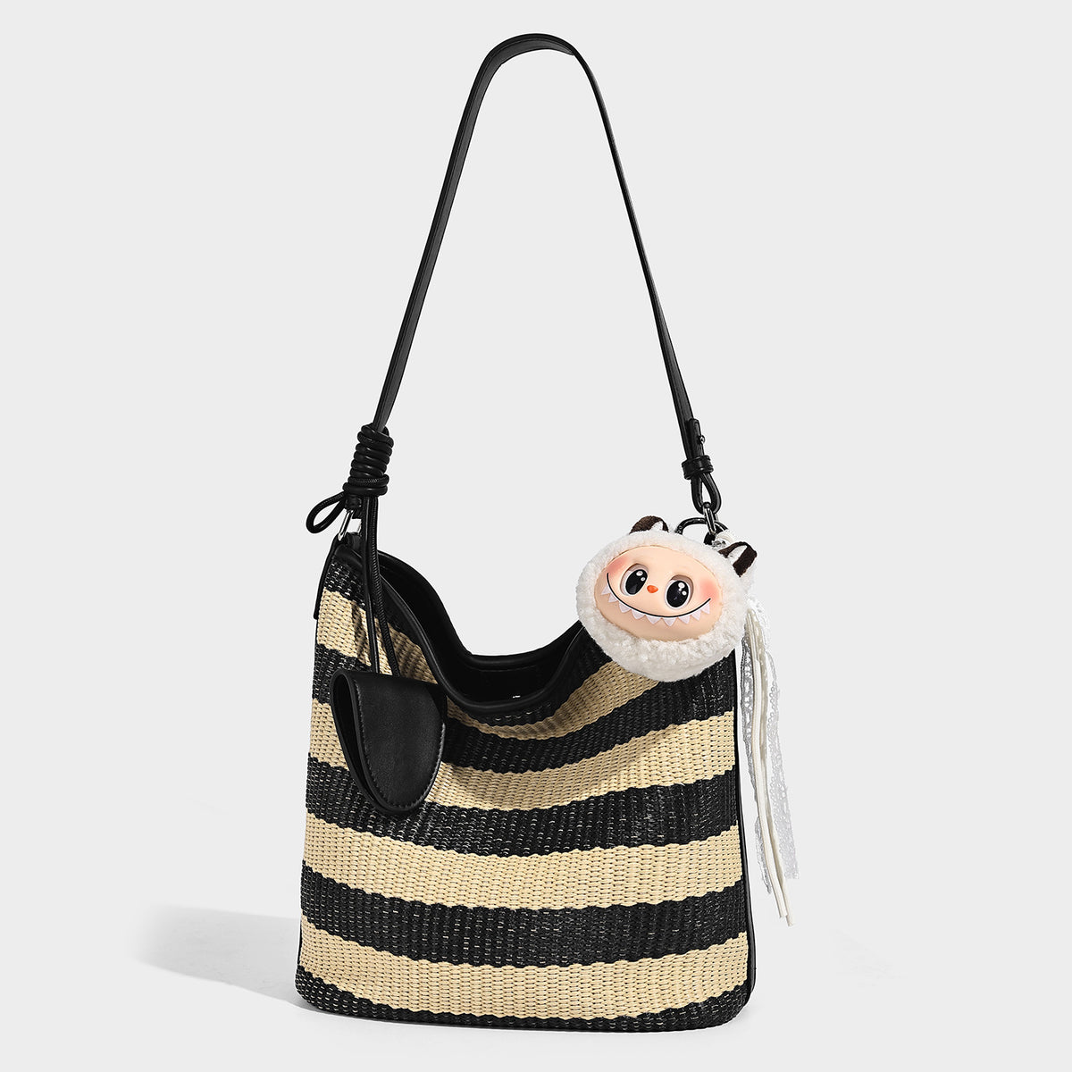 Black and beige striped woven bucket bag with leather-look black trim, open top, and long adjustable shoulder strap, front