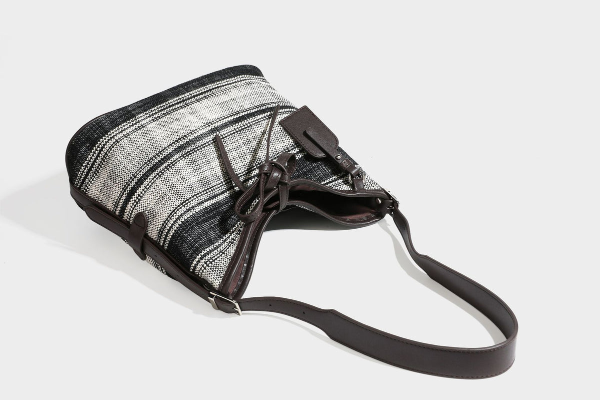 Schwarz-weiß karierte Hobo-Schultertasche aus gewebtem Material mit dunkelbrauner Einfassung in Lederoptik, Kordelzugverschluss und langem, verstellbarem