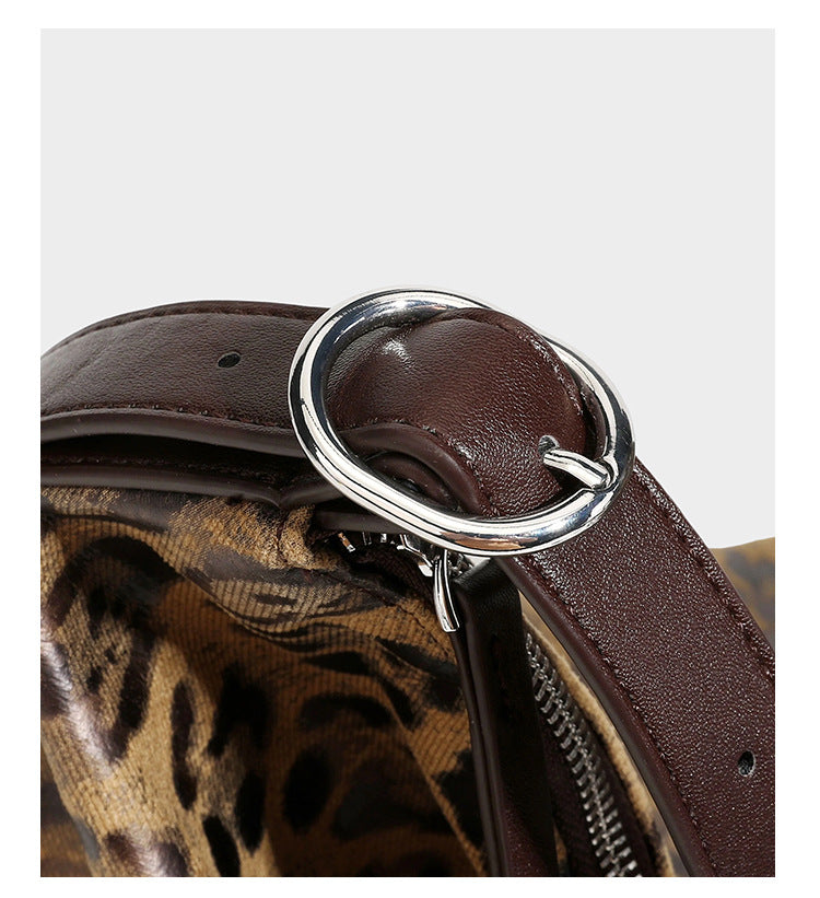 Slouchy leopard print hobo shoulder bag with glossy coated finish, top zipper closure, dark brown trim, and dangling charm