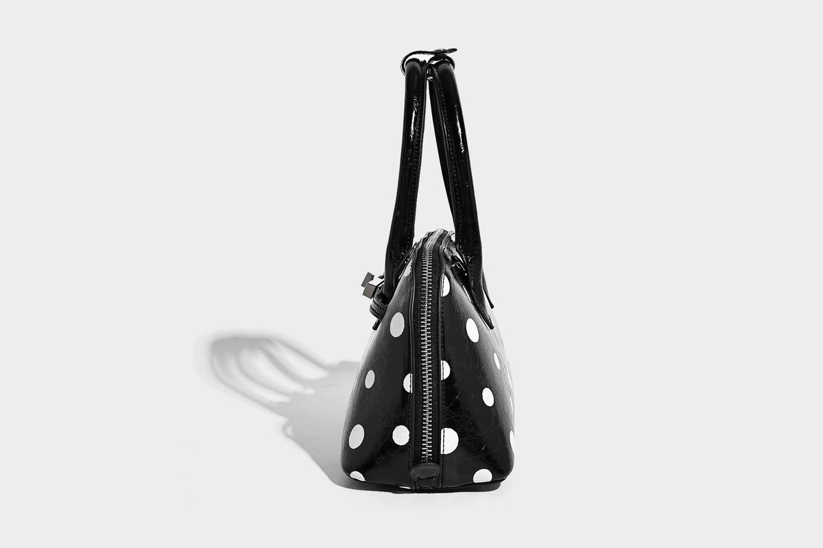 Glossy structured polka-dot satchel bag with dual top handles, silver turn-lock hardware, and detachable shoulder strap
