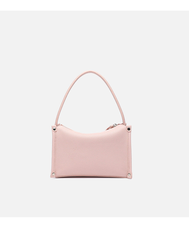 Small structured pebbled-finish convertible bag with silver corner studs, zip top, and detachable shoulder strap, detail view