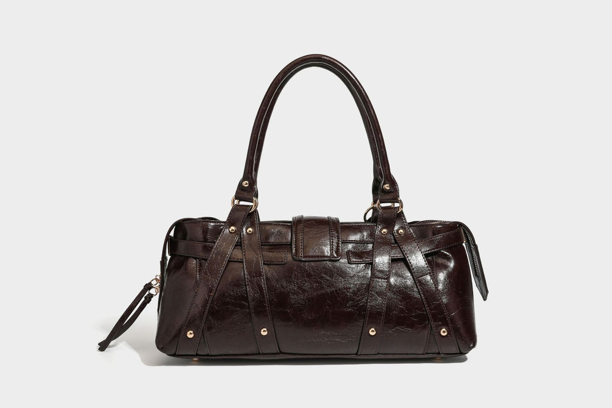 Glossy dark brown structured Boston satchel with heart-shaped lock charm, star pendant, rivet studs, multi-strap front panel
