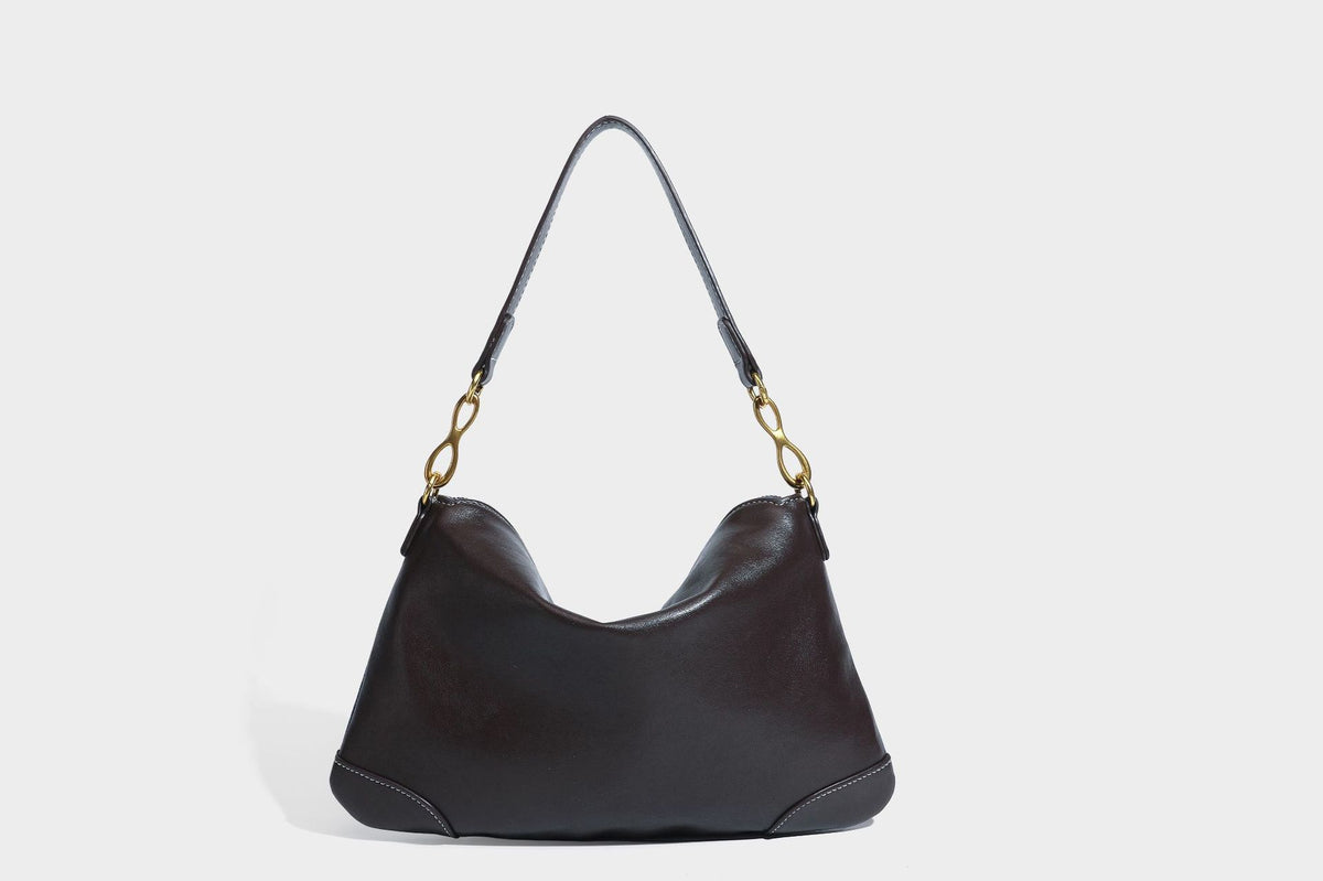 Slouchy denim shoulder bag with dark leather-look trim, gold-tone chain-link hardware, and top zipper closure, detail view 29