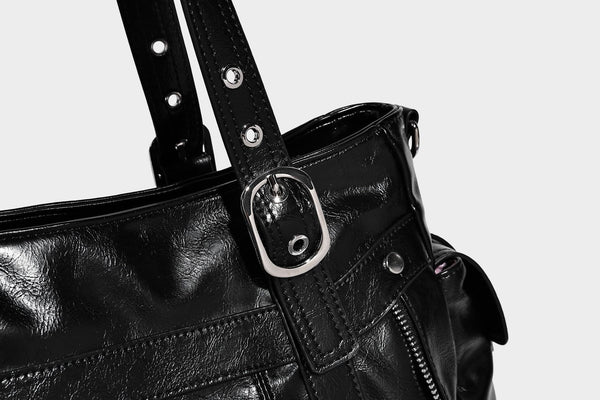 Glossy structured black tote shoulder bag with silver buckle hardware, zip pockets, dual top handles, and detachable, detail