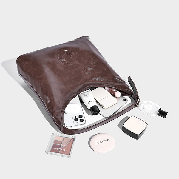 Glossy slouchy hobo shoulder bag with adjustable strap and embossed floral emblem, detail view 4