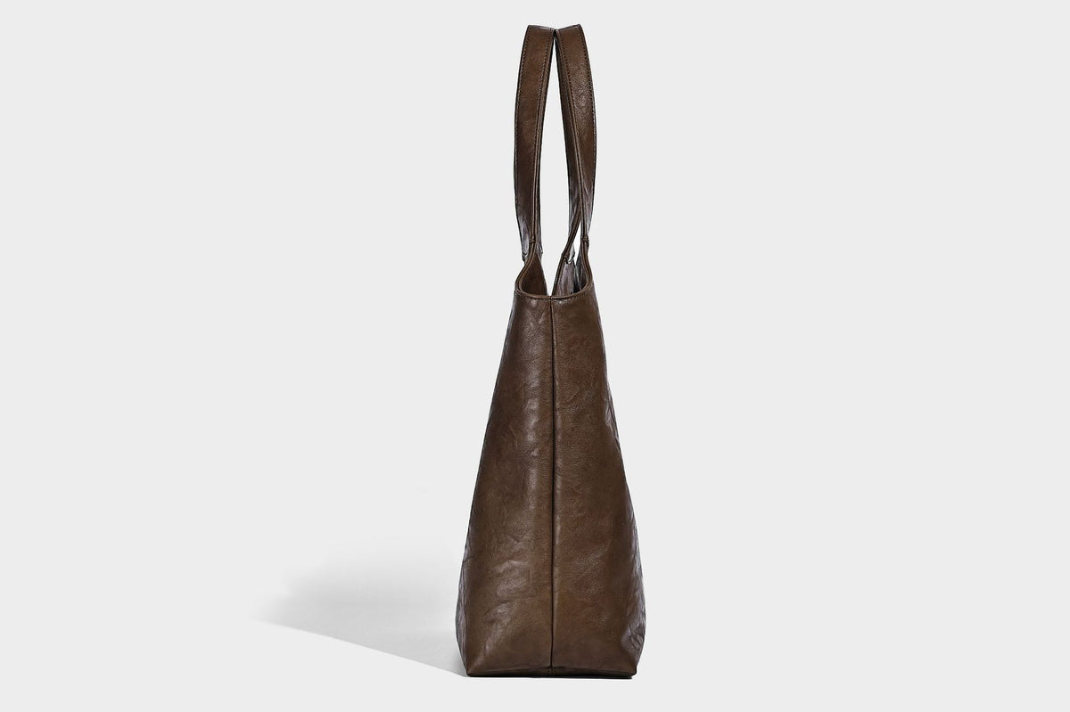 Large open-top tote bag with crinkled leather-look finish, long double shoulder straps, and embossed circular detail on