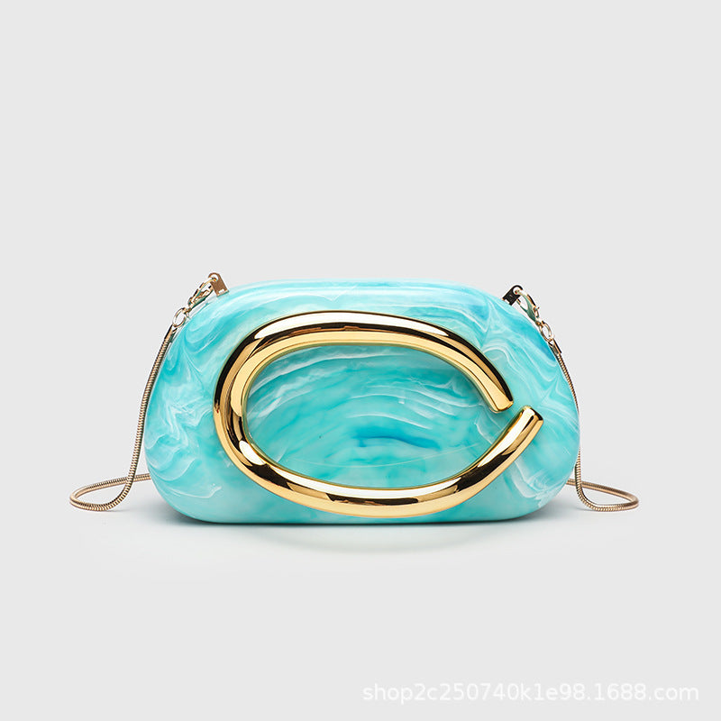 Kleine rechteckige Crossbody-Clutch mit abgerundeten Ecken, oversized poliertem C-förmigem Goldgriff und schmalem Goldkettenriemen, Detailansicht